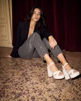 Sandalia de cuero offwhite con plataforma delantera, tacón ancho alto y tiras cruzadas en la parte delantera. Posee tiras envolventes en el tobillo con hebilla metálica dorada.