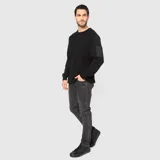 Sweater de punto negro con cuello redondo y manga larga. Presenta un bolsillo con cierre en la manga izquierda.