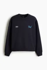 Buzo negro de algodón con diseño estampado en el pecho que incluye texto pequeño y el número '94 en celeste, corte holgado y hombros caídos.