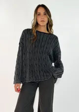 Sweater de punto con diseño de trenzas verticales, cuello redondo y corte holgado. Presenta un acabado texturizado con efecto lavado en color gris oscuro.