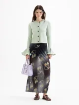 Cardigan negro de tejido de punto semi liviano, con calce al cuerpo, escote redondo y cierre frontal con botones. Mangas largas con puños godet acampanados que aportan volumen.