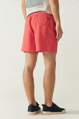Short de baño liso color coral con cintura elástica, cordón ajustable, dos bolsillos laterales y uno trasero.