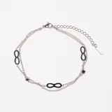 Pulsera plateada de doble cadena con dijes de infinito negros y pequeños dijes cuadrados.