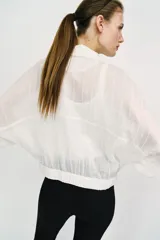 Blusa negra de cuello solapa y manga corta, con bolsillos con solapa en el pecho, bajo elástico y cierre frontal con botones.