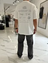 Remera oversize blanca de manga corta, con diseño gráfico estampado en la espalda en tonos grises que incluye la frase "The Bright Future" y varios motivos abstractos.