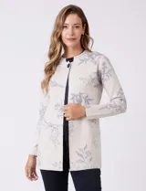 Cárdigan de punto marca Sioni, color beige con estampado floral en tonos azules. Presenta escote redondo a la base, cierre frontal con un botón metálico y mangas largas de corte recto.