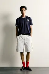 Polo de corte relajado confeccionado en tejido técnico, con diseño de rayas verticales en tonos azul marino y negro. Presenta cuello solapa con abertura frontal y detalles de rib en contraste en cuello y mangas. Incluye estampado frontal con el número 98 y la inscripción France, además de una etiqueta aplicada en el ruedo inferior.