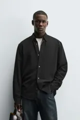 Camisa de corte regular fit confeccionada en tejido de algodón con textura de cuadrillé. Presenta cuello solapa, manga larga con puños abotonados y cierre frontal mediante botonadura.