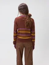 Sweater clásico de punto cable con cuello redondo a la base, mangas largas y fit al cuerpo. De color marrón con franjas horizontales violetas y amarillas, cuenta con el cuello, puños y ruedo acanalados, además de un pequeño logo bordado en el pecho.