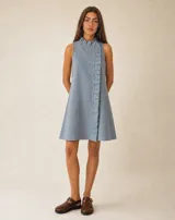 Vestido corto de lino color celeste, sin mangas, con cuello elevado y volado lateral que recorre la abotonadura frontal forrada.
