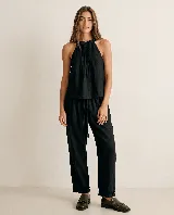 Pantalón de lino color negro, de silueta relajada, con cintura elastizada y lazo de ajuste. Cuenta con bolsillos laterales y terminación en el ruedo con volados sutiles.