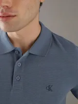 Chomba de piqué azul con cuello polo y tapeta de tres botones. Tiene mangas cortas, corte relaxed y logo de Calvin Klein bordado en el pecho. Confeccionada en algodón.