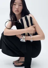 Vestido midi de algodón color negro, con cuello redondo, sin mangas y detalle de nudo lateral en la cintura que genera un drapeado sutil.