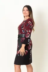 Vestido corto en jersey estampado color bordó con flores rojas y grises, de corte suelto con mangas 3/4 acampanadas y cuello redondo. Incluye cinturón ancho de cuero sintético negro con hebilla circular. 