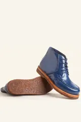 Bota acordonada de cuero vacuno con acabado charol color suela, con suela de goma tipo crepe y costuras reforzadas.