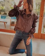 Camisa de algodón color marrón, con cuello clásico, cierre frontal de botones y mangas largas abullonadas con detalles de frunces elásticos y puños con volados.