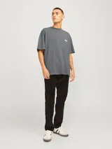 Camiseta Jack & Jones de manga corta, color gris con efecto desgastado, cuello redondo y fit loose. Presenta un pequeño texto estampado en el pecho.