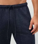 Pantalón de pijama tipo jogger color azul marino, con cintura elástica y cordón de ajuste. Presenta puños elásticos en los tobillos y un acabado jaspeado.