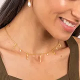 Collar dorado con cadena fina y dijes colgantes de perlas barrocas y piezas irregulares con textura.