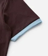 Remera de algodón color marrón con cuello redondo y bordes de las mangas en color celeste. Presenta una estampa frontal con el número 86 en color celeste.