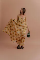 Vestido largo de tirantes finos, con escote en V y estampado de girasoles sobre fondo beige.