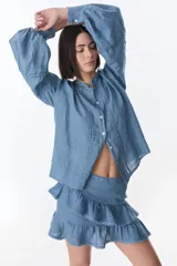 Camisa celeste de lino con botones, mangas largas abullonadas y detalles de crochet en el frente y los puños.