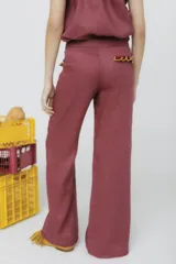 Pantalón de vestir mostaza, de corte palazzo, con bolsillos laterales y detalle de volados rojos en la cintura.