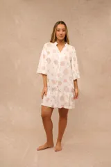 Vestido corto blanco con estampado marino de caracoles y estrellas de mar en tonos tostados, escote en V con cuello mao, mangas 3/4 y volado en el ruedo.