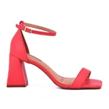Sandalias de tacón alto color coral, con tira delgada sobre los dedos, pulsera al tobillo con hebilla y tacón geométrico. Marca Korium, modelo Amilly.
