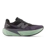 Championes de running New Balance Rebel V5 para mujer, color negro y morado oscuro con detalles en gris y suela gruesa en verde menta. Presentan tecnología de entresuela FuelCell y logo 'N' en el lateral.