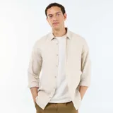 Camisa de lino de manga larga color beige, con cuello camisero y cierre frontal de botones.