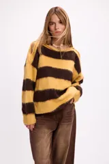 Buzo de tejido de punto con diseño de rayas horizontales anchas en color amarillo y marrón. Presenta cuello redondo, corte holgado y detalle de aberturas en los hombros.