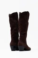 Bota de caña alta color chocolate, confeccionada en suede, con punta en pico y tacón bajo.