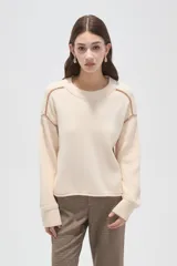Sweater de algodón color natural, de corte holgado y cuello redondo. Presenta detalles de costuras decorativas con bordado en los hombros y puños acanalados.