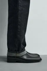 Bota estilo chelsea de cuero color marrón, con paneles elásticos laterales, tirador trasero y horma en punta con suela de tacón bajo.