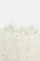 Vestido largo de encaje color blanco roto, con cuello alto, sin mangas y corte evasé. Incluye forro interior y cierre en la espalda.