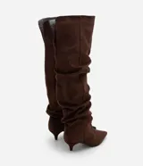 Bota over the knee color marrón, con acabado efecto gamuza y caída fruncida a lo largo de la caña. Presenta punta fina y tacón bajo y fino de 5 cm.