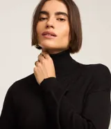 Vestido de punto negro, de manga larga y cuello alto, con corte recto y largo midi.