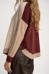 Sweater de punto con diseño color block en tonos beige, marrón y bordó, de cuello redondo y manga larga con puños acanalados en contraste.