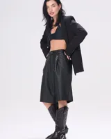 Bota texana de cuero negro con bordados en el caño, punta fina y correa con hebilla metálica.