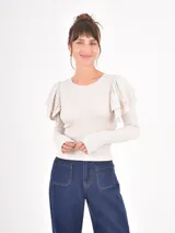 Remera de manga larga en color beige, confeccionada en tejido acanalado, con cuello redondo y detalle de volados en los hombros.
