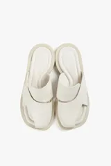 Sandalias planas de cuero color blanco hueso, con dos tiras anchas cruzadas en la parte superior y diseño minimalista.