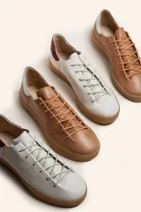 Zapatilla de cuero vacuno color azul marino, con cordones azules y suela de caucho color caramelo.