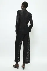 Pantalón de tiro alto confeccionado en encaje negro con diseño floral, de corte recto y largo cropped. Cuenta con forro interior a tono y cierre frontal con cremallera y ganchos metálicos.
