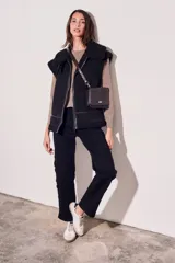 Chaleco negro con cuello de piel sintética, cierre frontal con cremallera y corte oversize.