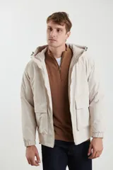 Campera impermeable negra con capucha, cierres a tono y cursores negros metalizados, bolsillos frontales con tapa, elásticos regulables en el ruedo e interior térmico con detalles confeccionados con láser.