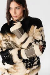 Mitones de cuero napalan con interior de piel sintética tipo corderito. Presentan costuras visibles y detalle de chapita metálica con logo.