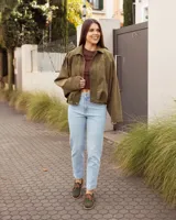 Zapatos náuticos de cuero verde oscuro, estilo mocasín con cordones de cuero marrón claro, costuras visibles en contraste y suela plana.