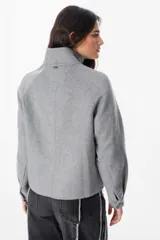 Chaqueta corta de paño color gris, con cuello alto, cierre frontal con cremallera y bolsillos delanteros con solapa.