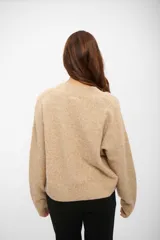 Buzo de tejido de punto en color beige melange, con cuello en V y mangas largas con puños acanalados.
